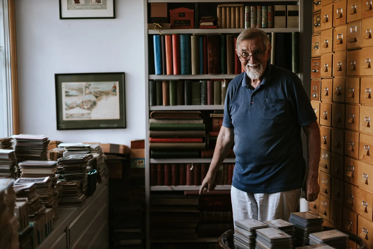 Sammler Walter Lukan, im Hintergrund hängt die größte je gelaufene Ansichtskarte gerahmt an der Wand. Sie misst 34 x 43 cm und wurde im Jahre 1898 verschickt. Foto: Victoria Nazarova