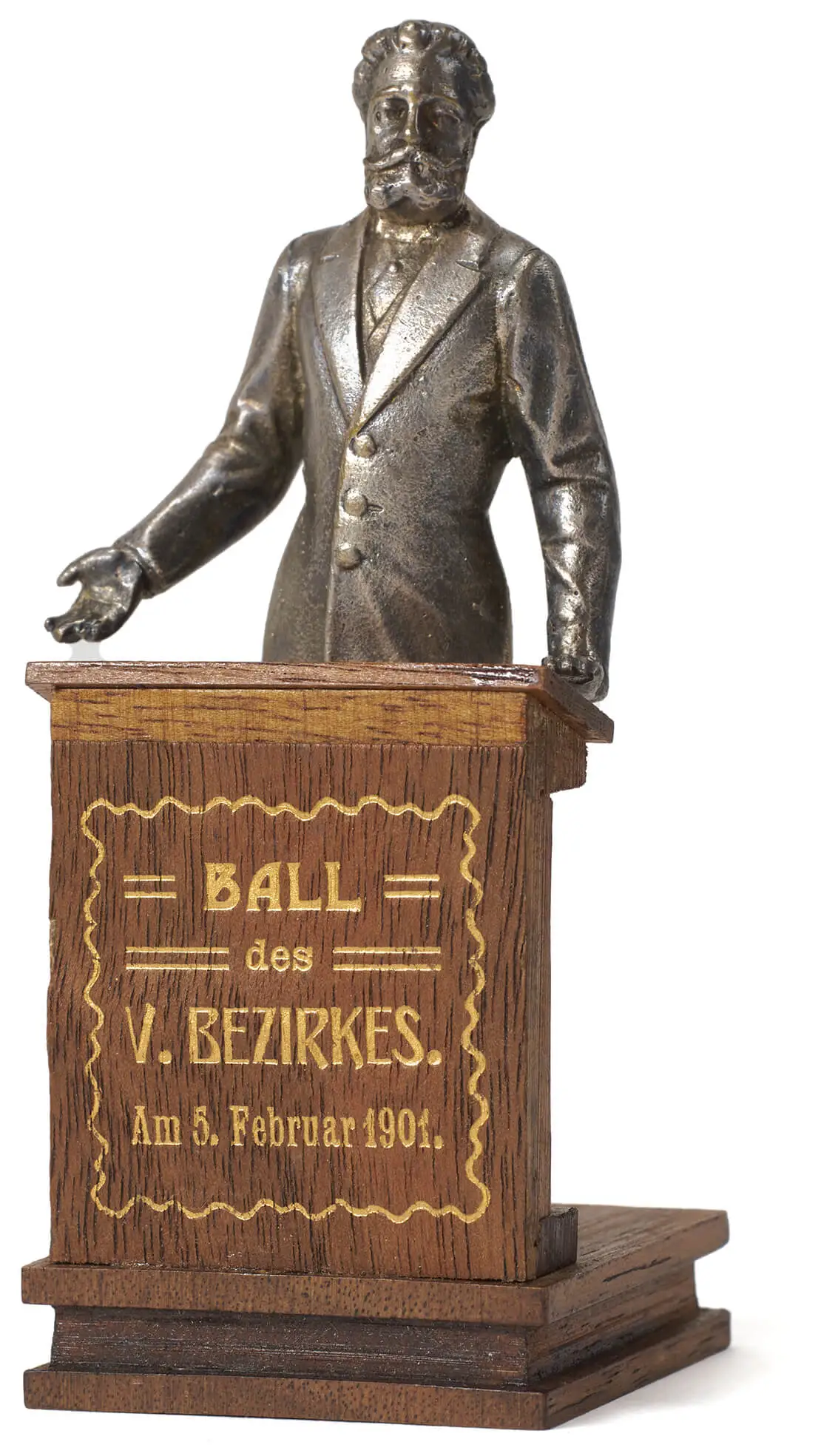 Blaudizek: Silberfarbene Metallstatuette Luegers am Holzrednerpult mit Schriftzug in Gold: „Ball des V. Bezirkes“, 5.2.1901, Foto: TimTom, Wien Museum  