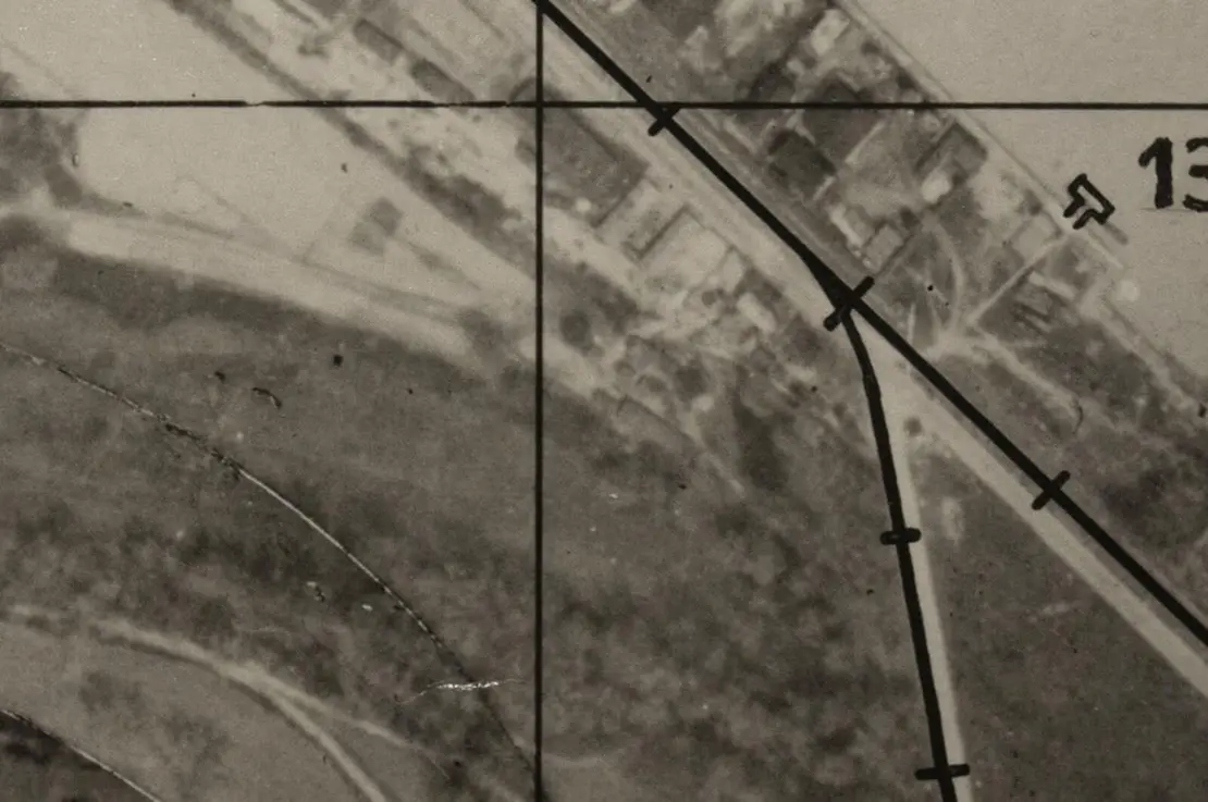 Dieses britische Luftbild aus der zweiten Junihälfte 1944 zeigt das Lager K 2 in Bildmitte (die längliche Baracke am Waldrand). Das Lager bestand bis dahin aus nur einer Wohn- mit anschließender Wasch- und Abortbaracke. Erst im Zuge der Arbeitskräfteaufstockung im Rahmen des Geilenberg-Programms erfolgte offensichtlich bis zum Herbst die Aufstellung einer zweiten Wohnbaracke, womit sich der Belag des Lagers von 70 auf 140 Zwangsarbeiter erhöhte. Quelle: WStLA   