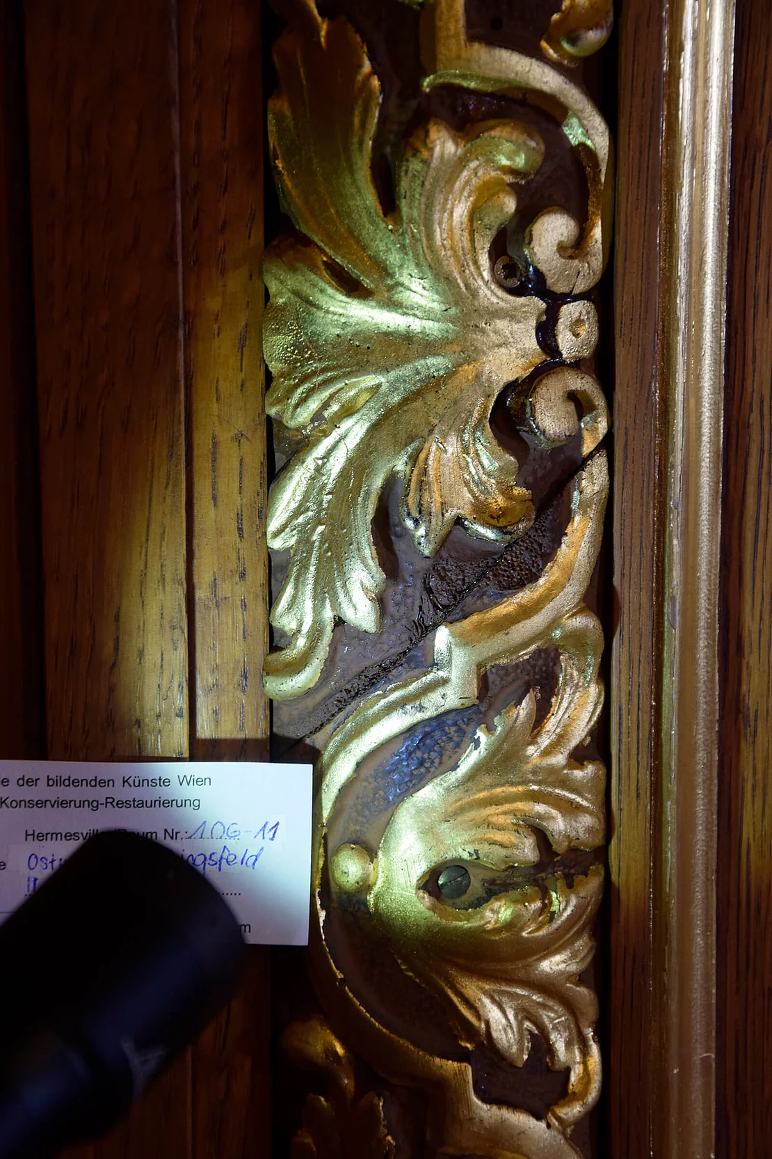 Detailaufnahme während der Untersuchungen der Stuckrahmen und Täfelung im Kirchensalon. Sichtbar ist hier ein Detail einer späteren Ergänzung in unbekanntem Material. Foto: Akademie der bildenden Künste Wien, Institut für Konservierung-Restaurierung