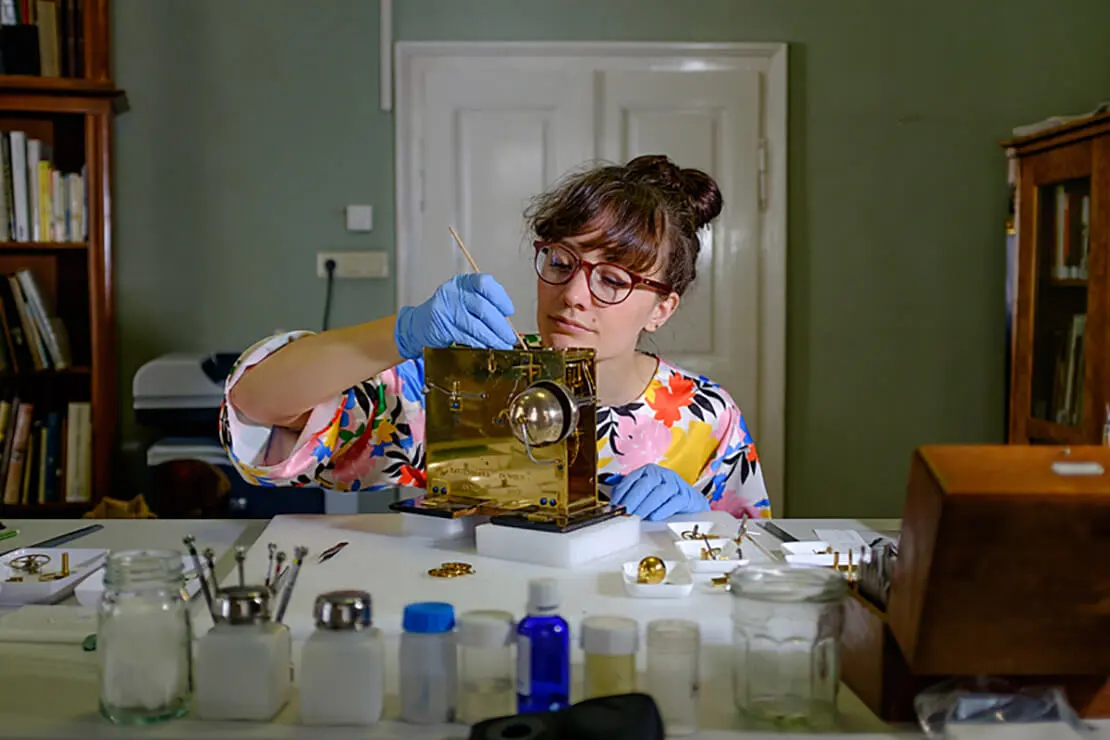 Restauratorin Tabea Rude beim beim Montieren und Einstellen des Uhrwerkes der Wanduhr von Mathäus Ratzenhofer, Wien, 1827, Foto: Michael Goldrei