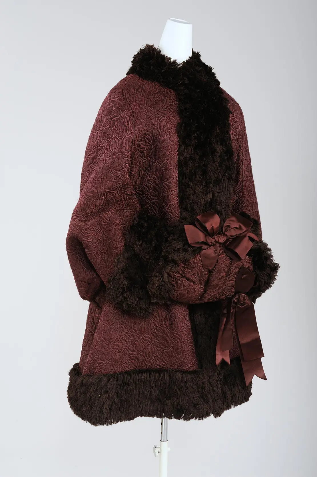 Passend zum Wintermantel ein Muff aus bordeauxrotem Seidenjacquard, verziert mit Satinmaschen und brauner Seidenfransenborte, 1860–1870, Wien Museum, Inv.-Nr. M 18565, Foto: Christin Losta