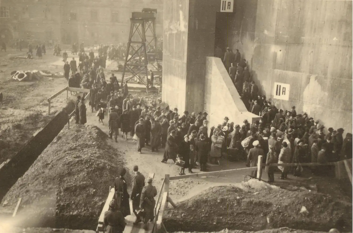 Das Bild zeigt lange Menschenschlangen, die sich bei Fliegeralarm vor dem Turm im Hof der Stiftskaserne bildeten. Deutlich sind die Bezeichnungen des Stiegenaufgangs IIA zu erkennen. Historisches Foto: Schiffmann, zur Verfügung gestellt von Marcello La Speranza.