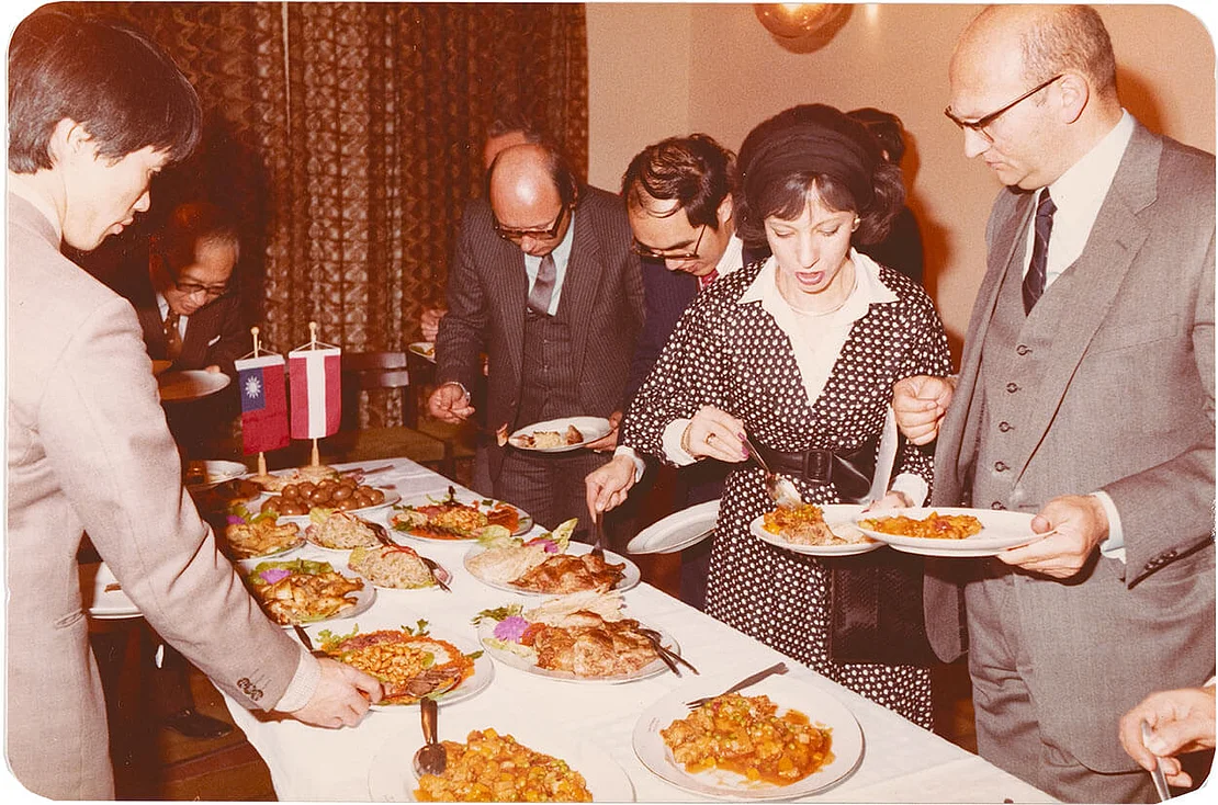 Neben einer großen Auswahl kulinarischer Spezialitäten, stehen auch die Flaggen der Flaggen der Chinesischen Republik (Taiwan) und Österreichs Seite an Seite am Buffet, Dezember 1979, Foto: Heinz Pfeifer / Schikola, Familie Wu  