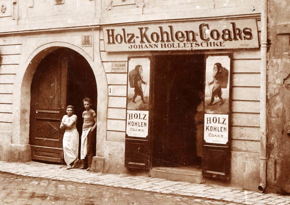 Neustiftgasse 55, Ausschnitt aus einer Ansichtskarte aus dem Verlag Reinhold Entzmann & Sohn, um 1906, mit den Geschäftsschildern der Firma Johann Holletschke (Kohlenträger) auf den Innenseiten der Türflügel des Geschäftslokales. 