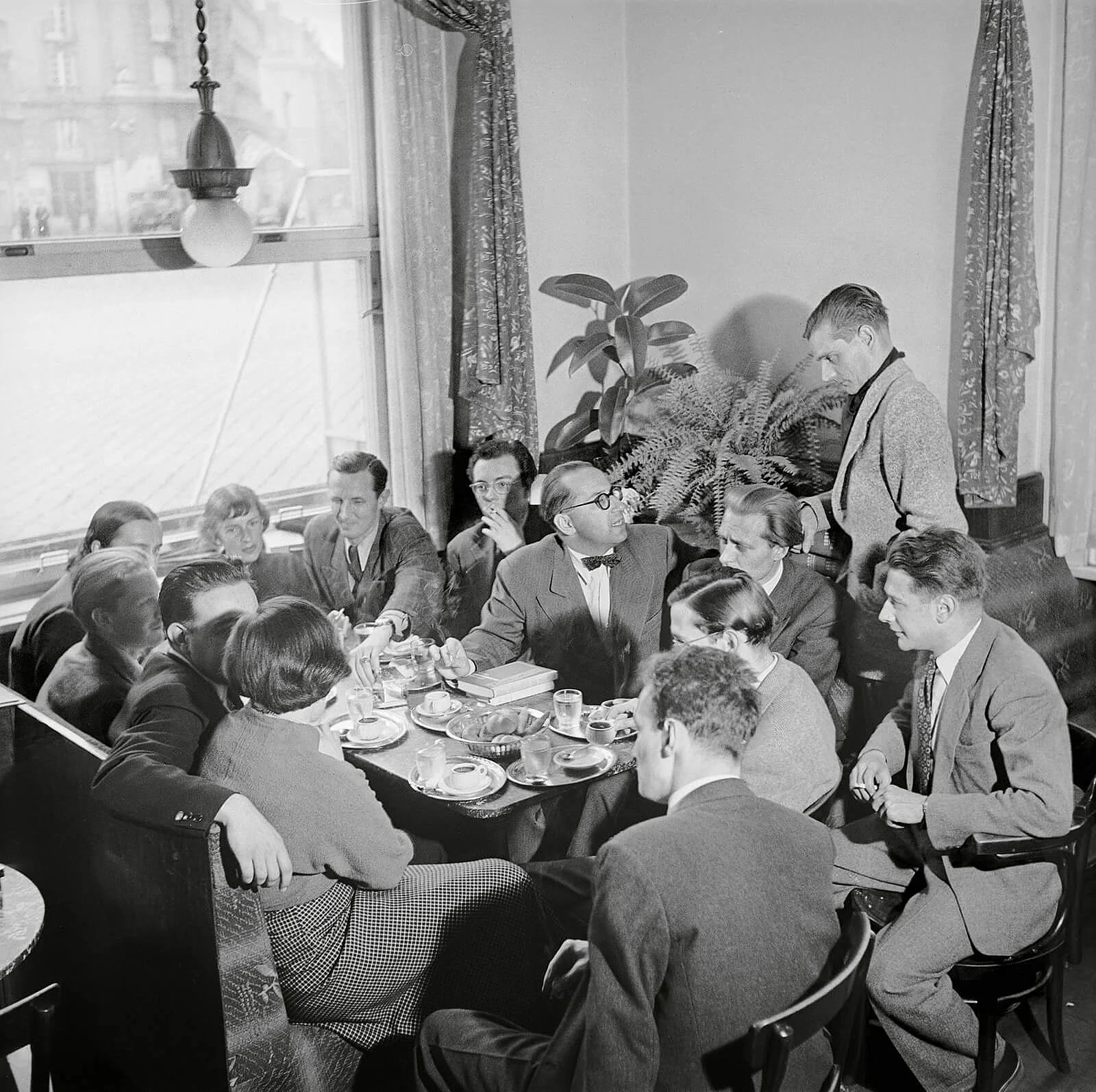 Die vom Fotografen Franz Hubmann inszenierte literarische Bohème im Café Raimund um 1951, (Bild-)Mittelpunkt ist der Kritiker Hans Weigel (mit Fliege), Jeannie Ebner links vor dem Fenster. Foto: Franz Hubmann / brandstaetter images / picturedesk.com   