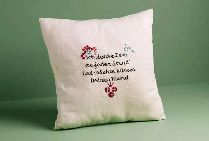 Per Postkarte hat eine Wienerin 1915 diese Botschaft an ihre Geliebte geschickt. Das Zitat wurde nun von der Künstlerin Anja Melzer auf einen Kaprizpolster gestickt, der in der neuen Ausstellung von QWIEN zu sehen ist. Foto: Gregor Hofbauer, QWIEN