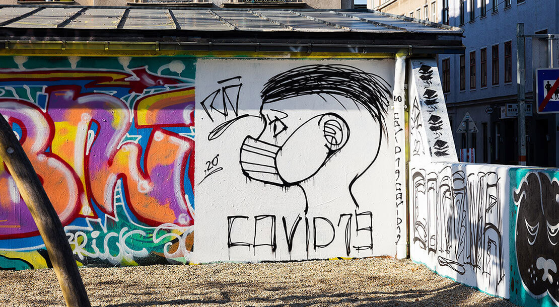 Person im Profil mit Atemschutzmaske begleitet von „Covid 19“ und „Corona“. Rio, Yppenplatz, März 2020, Foto: Elodie Grethen, Wien Museum 