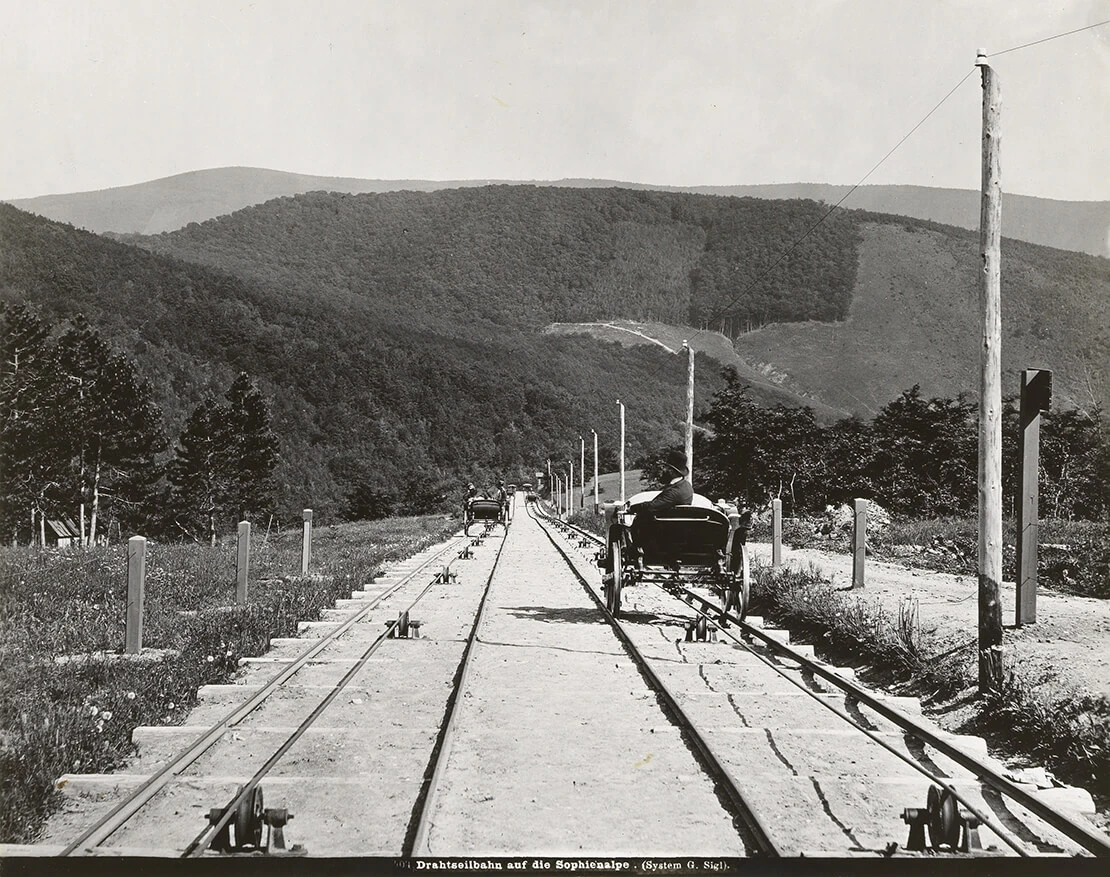 Drahtseilbahn auf die Sophienalpe mit Blick ins Tal, Fotografie von Michael Frankenstein, um 1875, Wien Museum. Vor allem in die Fotografien der Sophienalpen-Bahn ist das Thema der Bequemlichkeit der Fahrt bei gleichzeitiger Möglichkeit, die Fernsicht zu genießen, eingeschrieben.