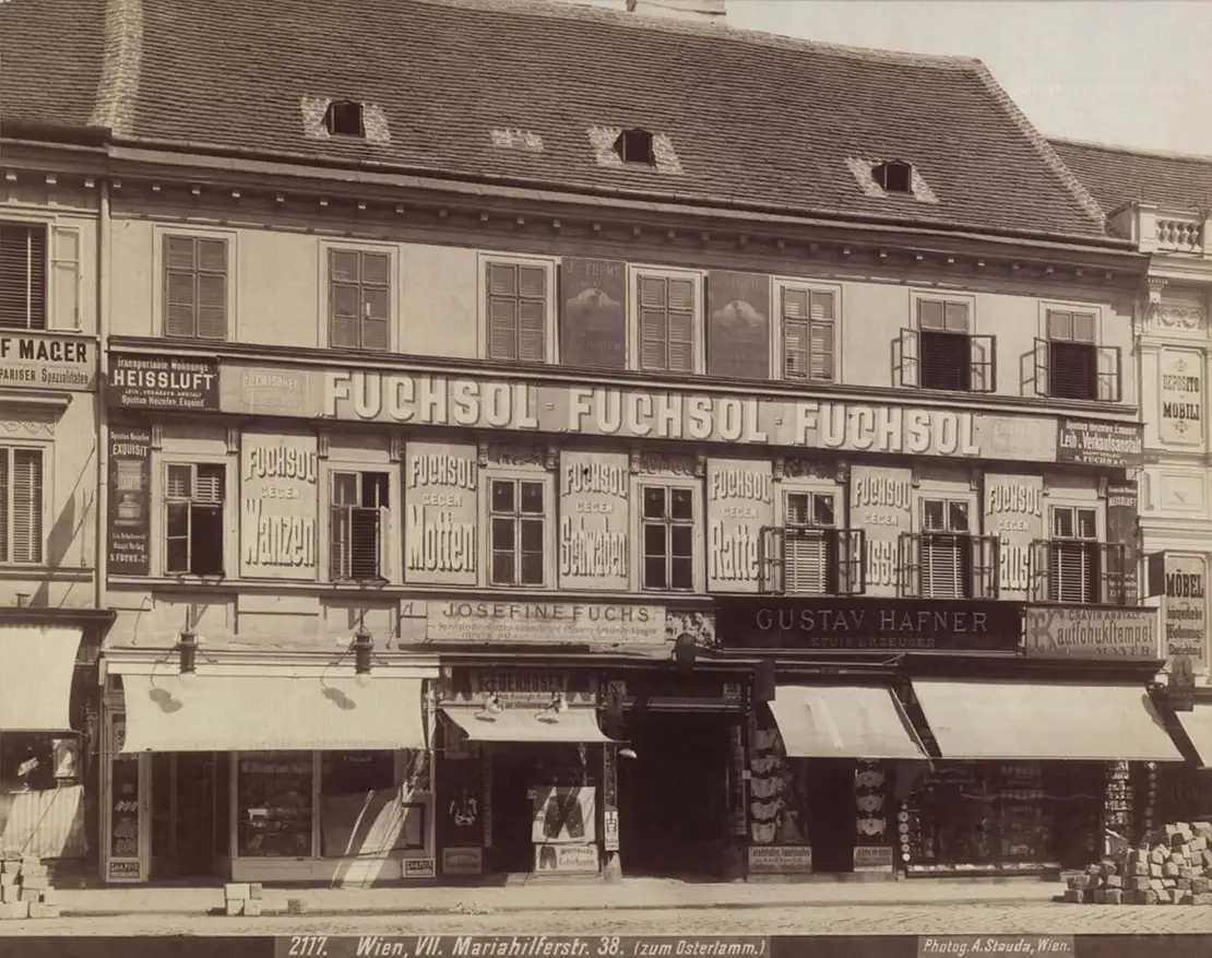 Mariahilfer Straße 38, Werbeschilder des chemischen Laboratoriums „Fuchsol“ am Haus „Zum Osterlamm“, das Hauszeichen über dem Portal zur Hälfte überdeckt von Firmentafeln, Fotografie von August Stauda, um 1905, Wien Museum.